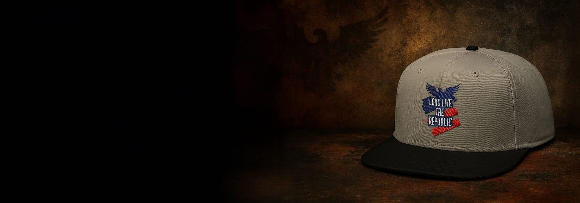 Light gray and black snapback hat with the words Long live the republic on it, on rustic brown background